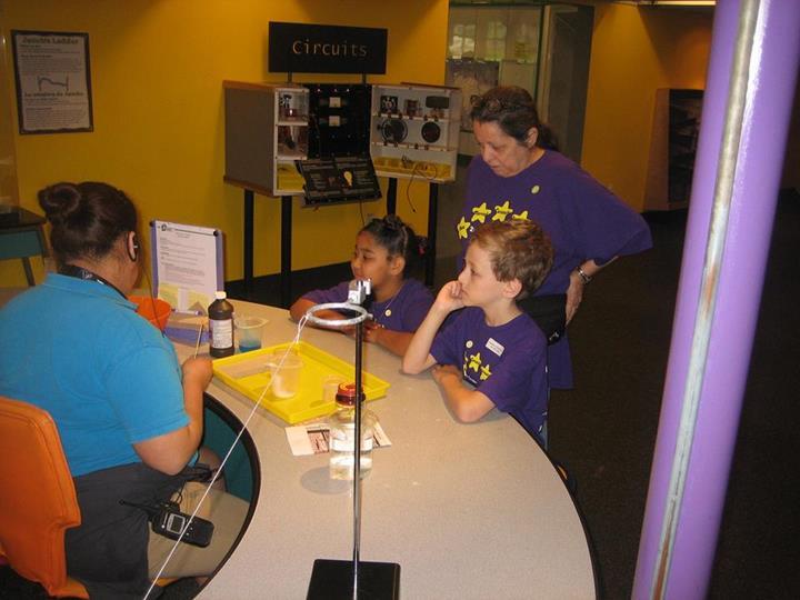 Robert Thompson and Lydia Cook watching one of the museum volunteers perform an experiment.